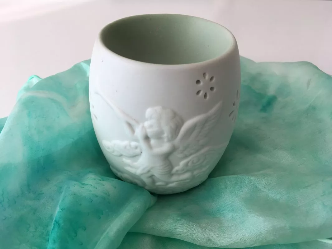 Porcelánová aroma lampa Ochranný anděl v bílé barvě s reliéfem andělíčků na světlém pozadí“