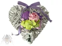 Bílé proutěné závěsné srdce zdobené fialovou a růžovými růžemi, fialovými a zelenými květy a fialovou mašlí