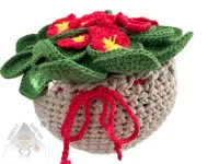 Háčkovaná primulka s červenými květy a zelenými listy – ruční dekorace