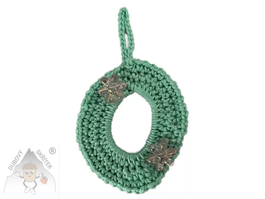 Háčkované vajíčko s poutkem na zavěšení, ozdobené dvěma třpytivými kvítky.